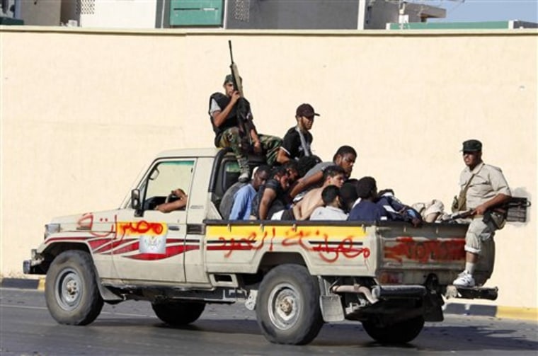 Libyan rebels secure prisoners in the back of a pick-up truck during fighting in Tripoli, Libya. The graffiti on the truck, in Arabic, reads, "Misrata steadfastness." 